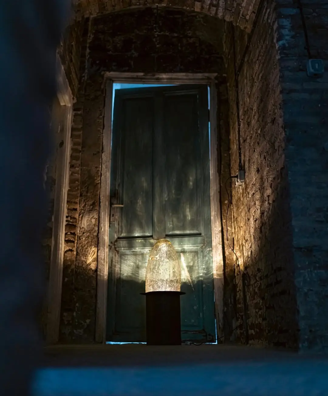 A glowing lamp in front of an old weathered door