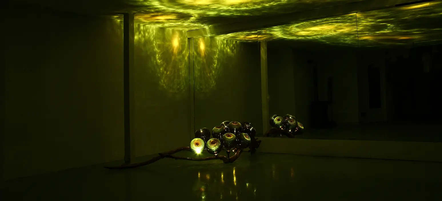 A lighting piece casting reflections across a dark room